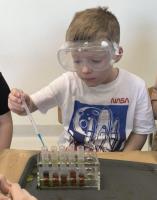Zdjęcie przedstawia dzieci wykonujące eksperymenty chemiczne.