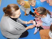 Przedszkolak ćwiczy szczotkowanie na dużym modelu szczęki podczas zajęć z dentystką.
