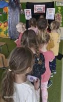 Zdjęcia przedstawiają przedszkolaki biorące udział w zabawie teatralnej z okazji Międzynarodowego Dnia Teatru. W tle widać teatralną scenografię oraz przedszkolną salę z zabawkami i kolorowymi meblami. 