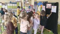 Zdjęcia przedstawiają przedszkolaki biorące udział w zabawie teatralnej z okazji Międzynarodowego Dnia Teatru. W tle widać teatralną scenografię oraz przedszkolną salę z zabawkami i kolorowymi meblami. 