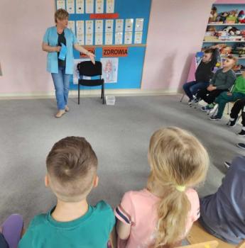 Dzieci z grupy „Malinki” słuchają z zaciekawieniem opowieści pani pielęgniarki. Dzieci oglądają przybory medyczne podczas zajęć o zdrowiu.
