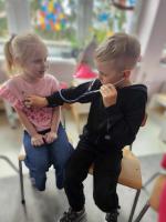 Dzieci z grupy „Malinki” słuchają z zaciekawieniem opowieści pani pielęgniarki. Dzieci oglądają przybory medyczne podczas zajęć o zdrowiu.