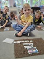 Dzieci biorące udział w zajęciach o kosmosie – oglądają ilustracje planet, bawią się w kosmiczną podróż i wykonują tematyczne zadania.
