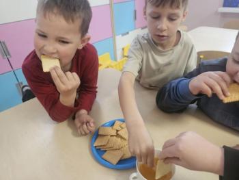 Dzieci z grupy „Malinki” uczestniczące w zajęciach z okazji Dnia Pszczoły – bawią się, uczą o pszczołach i degustują miód.